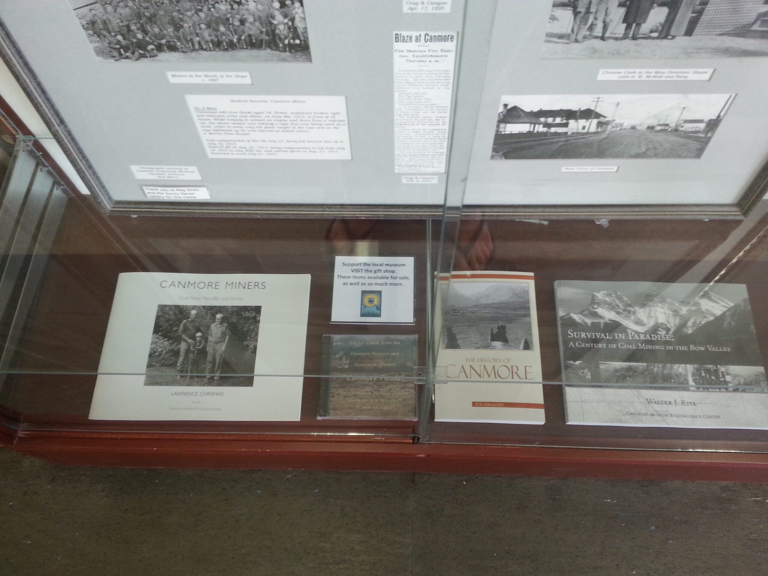 Museum showcase with books on the history of Canmore, and some old black and white photographs of the town.